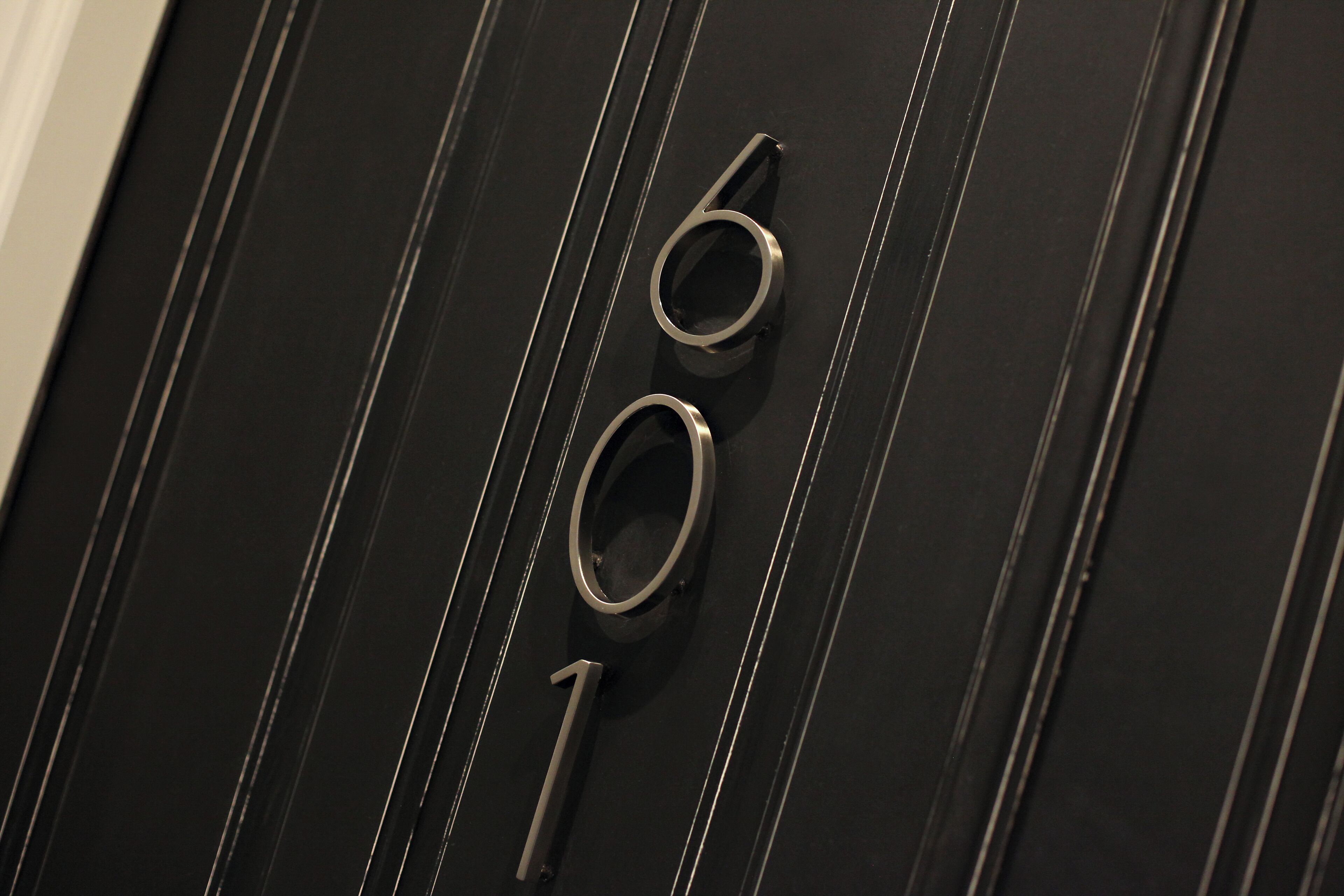 A close-up of a black door with a number '6' and '1' indicating room numbers.