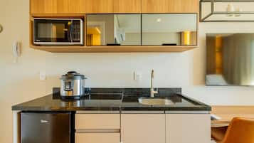 A modern kitchen with a microwave, stove, sink, and a refrigerator.