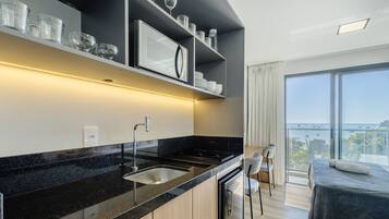 A modern kitchen with a black countertop, stainless steel sink, and a dining area with chairs and a table.