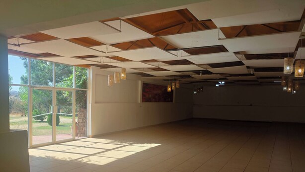 Una stanza spaziosa con soffitto alto, ampie finestre e lampade a sospensione.