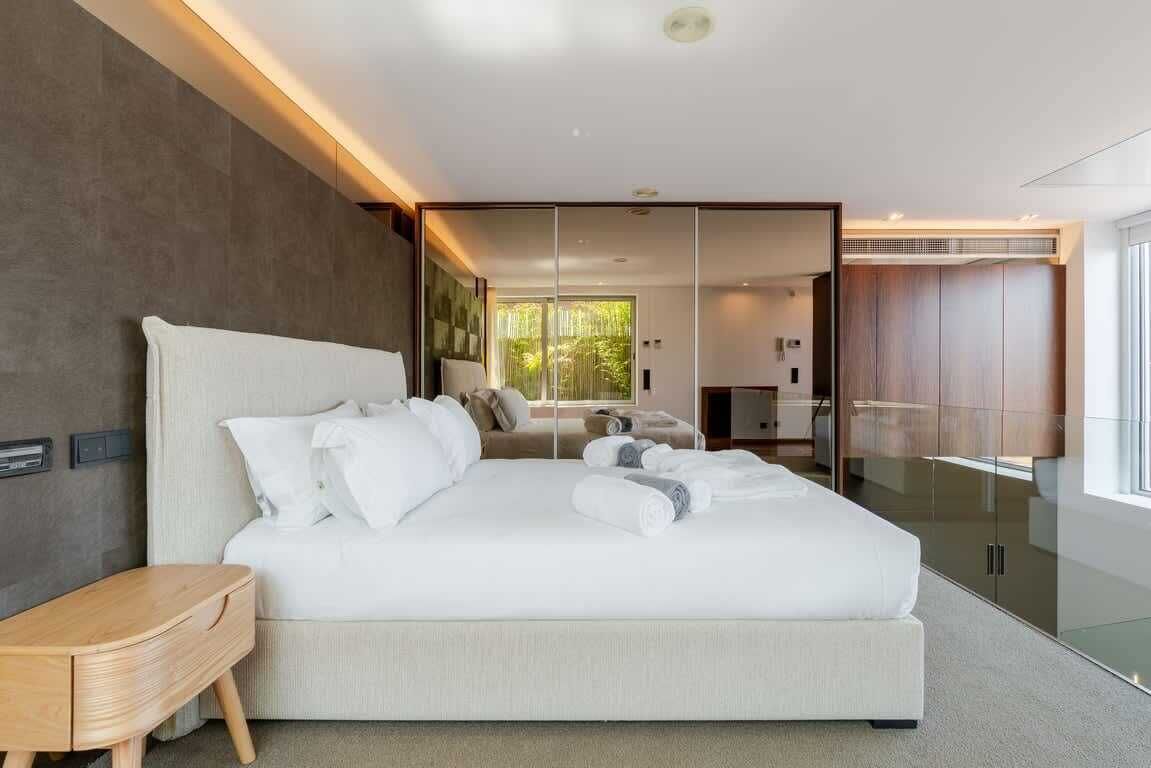 A modern bedroom with a large bed, a bedside table, and a wardrobe.