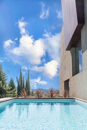 A swimming pool with clear blue water, surrounded by a modern building with a tiled border, and a clear sky with clouds. - Skyline Retreat with pool by Portugal Active (Viana do Castelo)