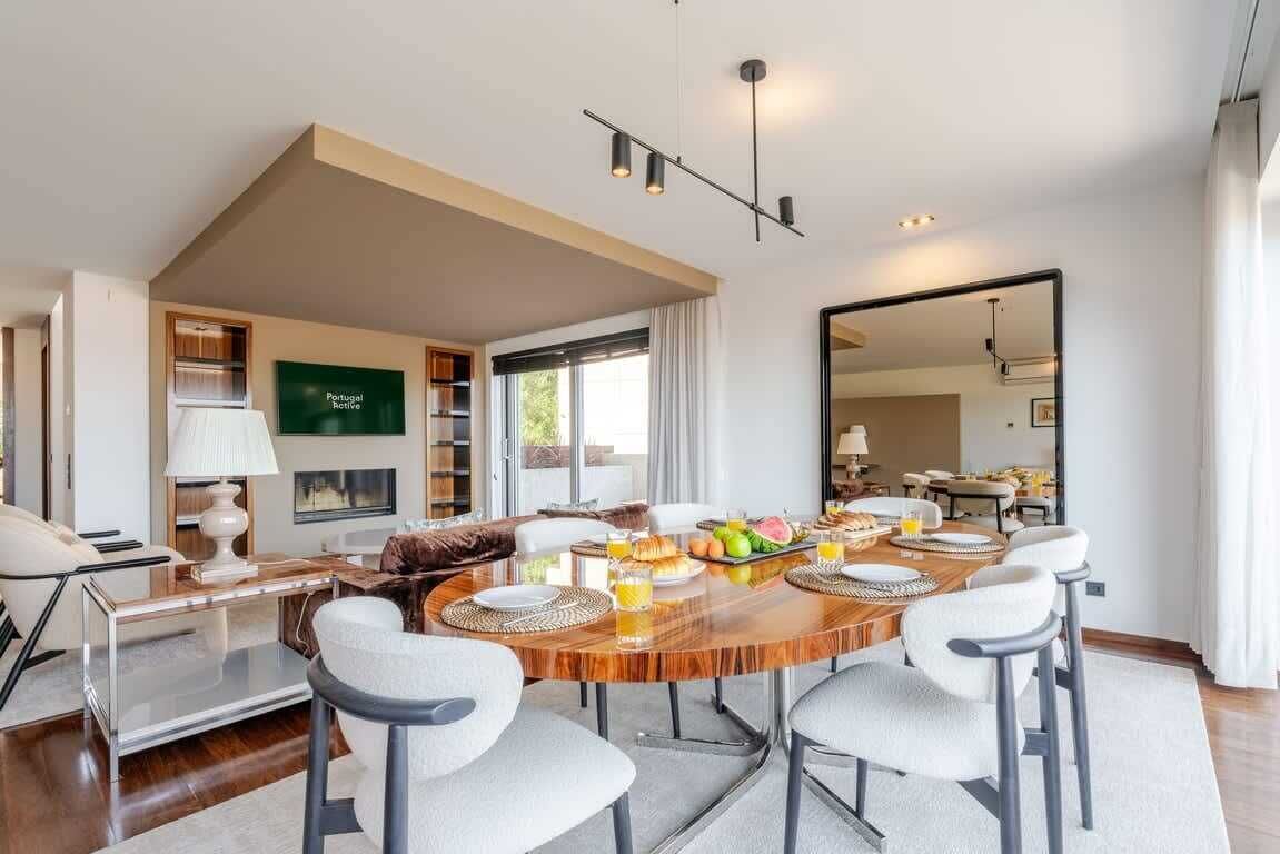 A modern dining area with a wooden table, white chairs, and a breakfast setting.