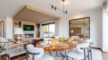 A modern dining area with a wooden table, white chairs, and a breakfast setting.