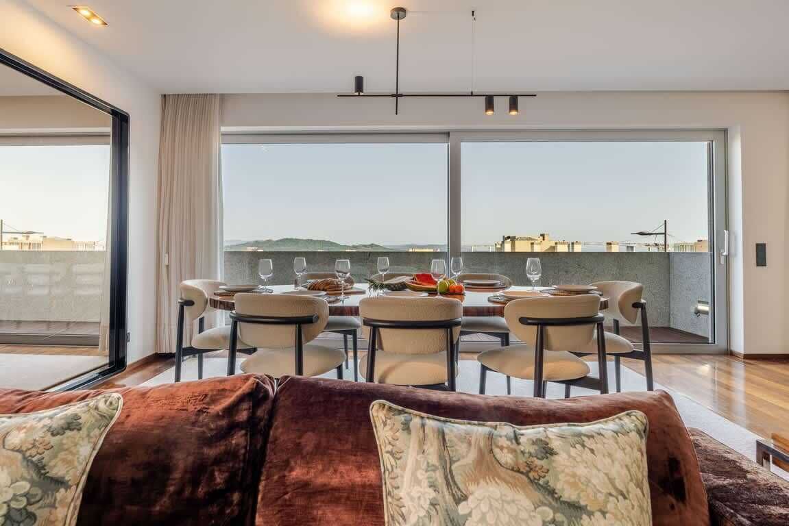 A dining area with a table set for six, large windows, and a view of the cityscape.