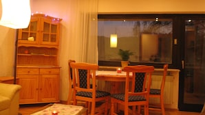A cozy dining area with wooden furniture, a table, chairs, a cabinet, and a window with a view. - Vacation cottage Wasgaublick (Bundenthal, Rheinland-Pfalz, Deutschland)