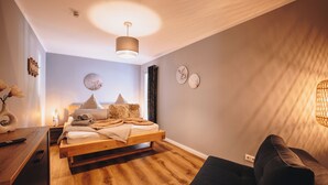 Quarto moderno com cama de madeira, mesas de cabeceira, escrivaninha e uma cadeira.