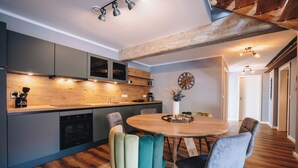 Cozinha moderna com armários cinza, bancada de madeira e área de jantar com mesa e cadeiras redondas.