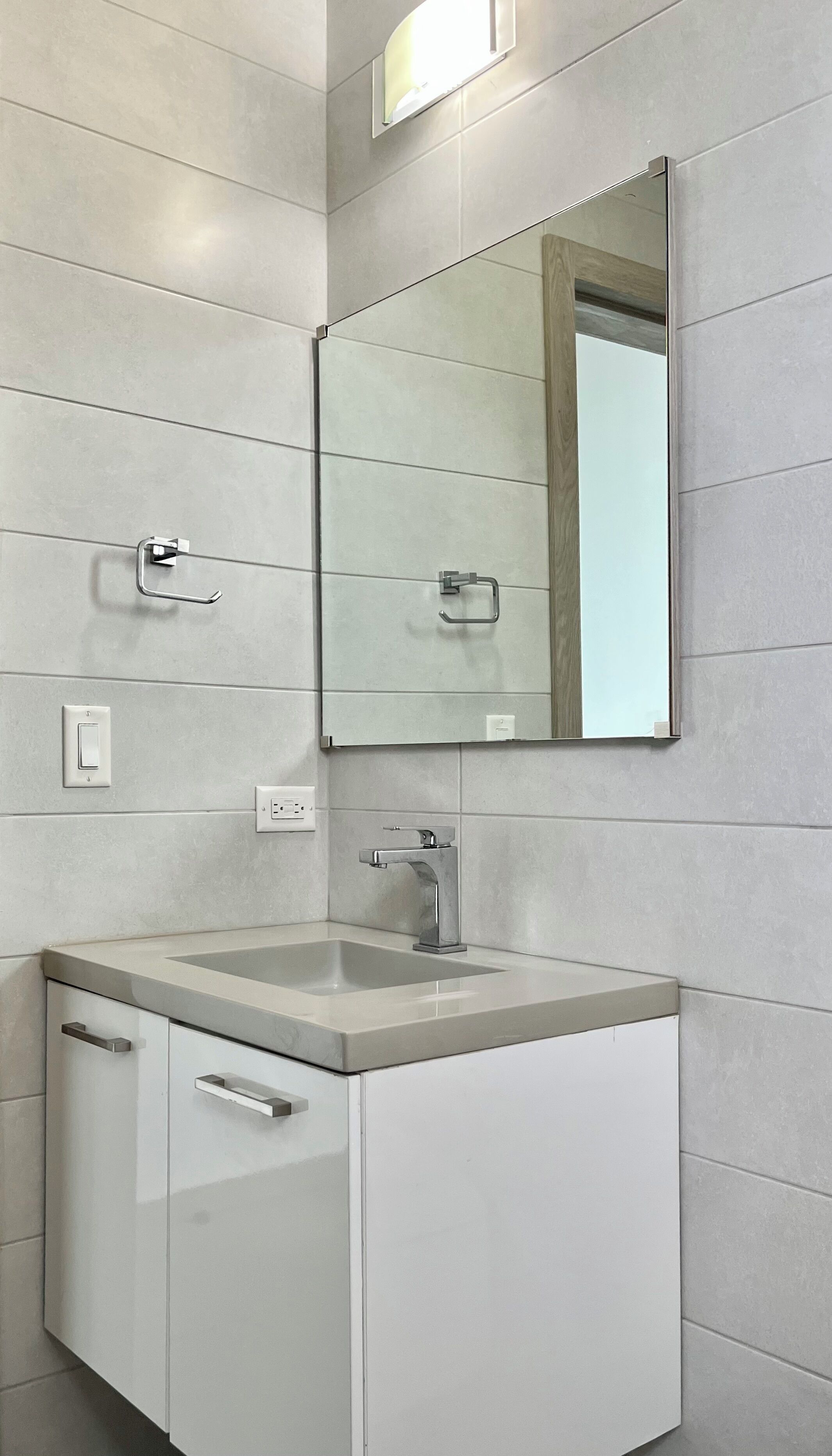 Une salle de bain moderne avec un grand miroir, un lavabo et un meuble.
