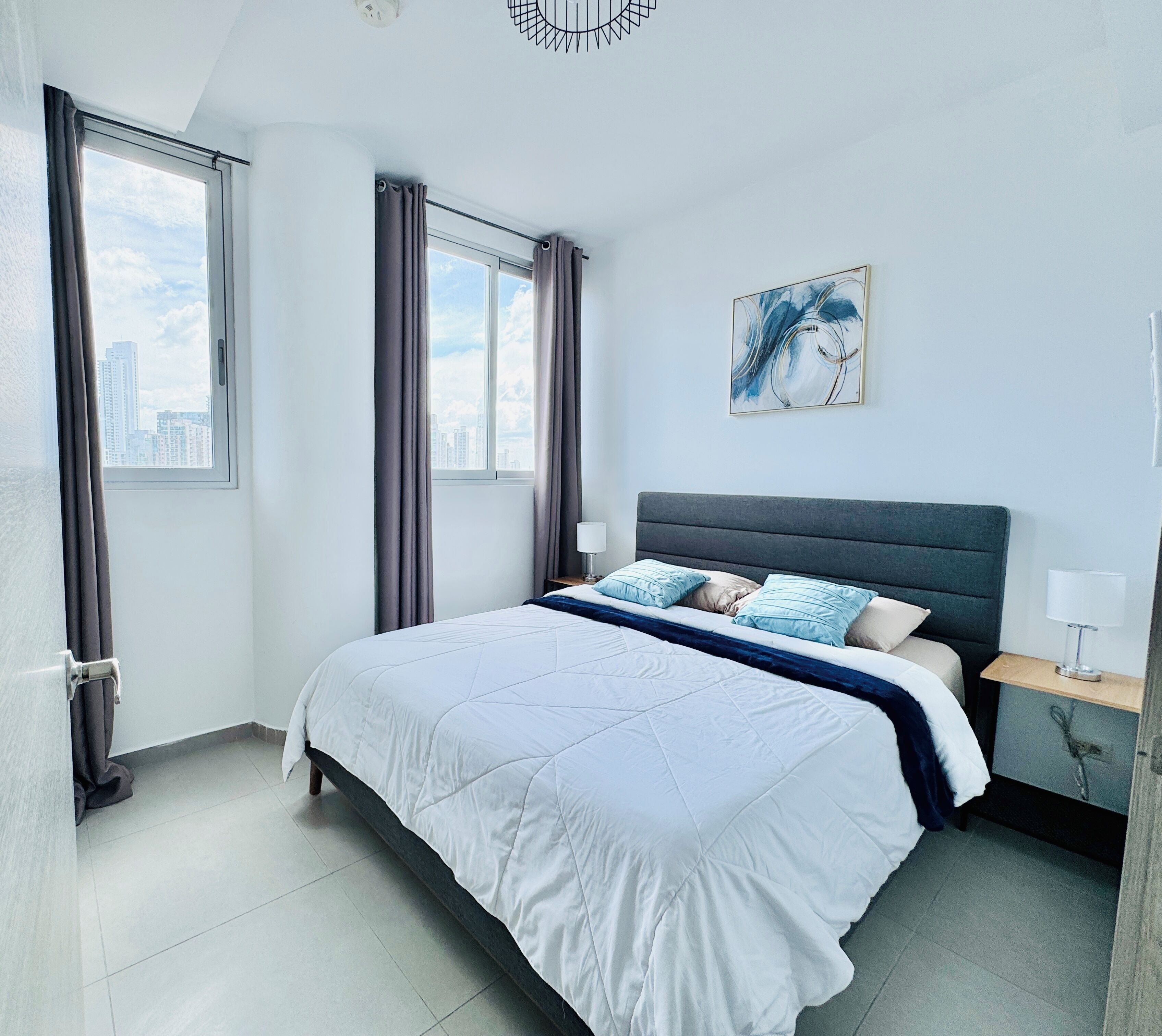 Un dormitorio moderno con una cama grande, vistas a la ciudad y un cuadro en la pared.