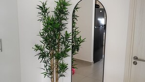 A room with a large mirror, a potted bamboo plant, and a closed door. - Charming  pool view apartment at Serena village, with Beach access in Punta Cana (Punta Cana)