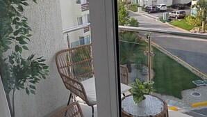 A balcony with wicker furniture and a small table with a plant. - Charming  pool view apartment at Serena village, with Beach access in Punta Cana (Punta Cana)