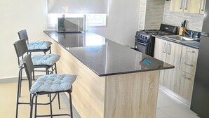 A modern kitchen with a central island, bar stools, a stove, and a refrigerator. - Charming  pool view apartment at Serena village, with Beach access in Punta Cana (Punta Cana)