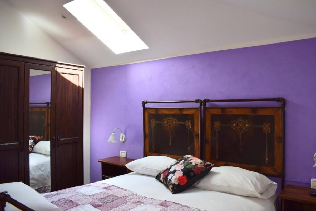 A bedroom with a bed, a nightstand, a mirror, and a wardrobe.
