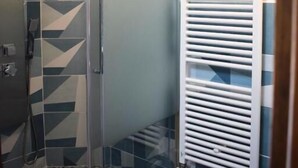 A shower with a glass door, a white radiator, and patterned tiles. - IL GINEPRO R&B (Monghidoro)