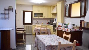 A compact kitchen with a dining table, chairs, a microwave, and a sink. - IL GINEPRO R&B (Monghidoro)