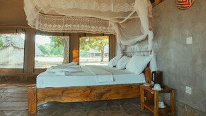 Una cama con dosel, una mesita con hervidor y vistas al exterior.