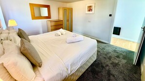 Habitación de hotel con una cama, un aparador, un espejo y una puerta que da a un balcón.