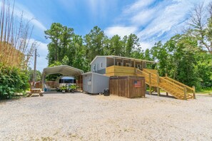 A rustic cabin with a covered porch, a wooden staircase, and a gravel driveway. - Charming 2-bedroom barn in, Foley 8 miles to Beach, dogs welcome, near Sportplex (Foley)