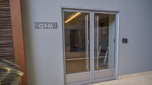 A gym entrance with a sliding glass door, a sign above the door, and a security keypad on the wall.