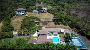 An aerial view of a residential property with multiple buildings, a swimming pool, and a tennis court.