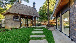 A modern building with a stone facade, a glass entrance, and a well-maintained lawn with a stone pathway. - Beautiful Apartments in Gramado - DMS (Gramado)