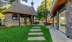 A modern building with a stone facade, a glass entrance, and a well-maintained lawn with a stone pathway.