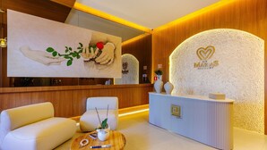A reception area with a modern design, featuring a reception desk, seating area, and a large artwork on the wall. - Beautiful Apartments in Gramado - DMS (Gramado)
