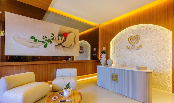 A reception area with a modern design, featuring a reception desk, seating area, and a large artwork on the wall. - Beautiful Apartments in Gramado - DMS (Gramado)