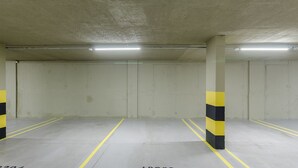 A parking garage with concrete pillars and yellow lines on the floor. - Beautiful Apartments in Gramado - DMS (Gramado)