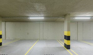 Eine Parkgarage mit Betonstützen und gelben Linien auf dem Boden.