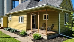 Una casa amarilla con porche, puerta y ventana.