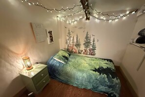 Ein Schlafzimmer mit Bett, Nachttisch, einer Wandablage und Lichterketten.