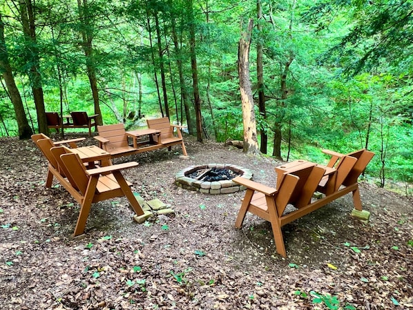 A forested campsite with wooden benches and a fire pit.