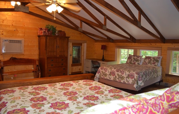 A bedroom with a wooden ceiling, a bed with floral bedding, a dresser, and a chair.