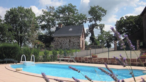 Ein Steinhaus mit Schwimmbad, umgeben von Bäumen und Lavendel.
