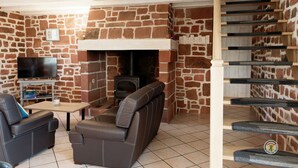 Ein gemütlicher Wohnbereich mit Steinwand, Kamin, Sofa und Fernseher.