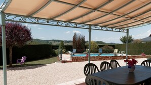 Ein überdachter Außenbereich mit Pool, Stühlen und einem Tisch.