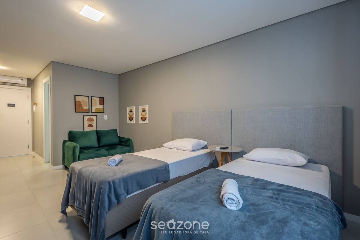 Ein Hotelzimmer mit zwei Betten, einem grünen Sofa und einem kleinen Tisch.