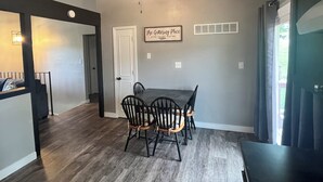 Un espace repas comprenant une table et des chaises, un ventilateur de plafond et une porte.