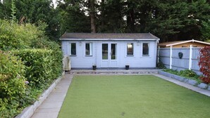 A small, single-story house with a white exterior and a green lawn in front. - Modern cabin in residential area near 2 train stations with mainlines to London (Orpington)