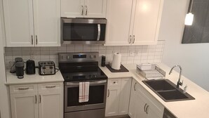 Een moderne keuken met witte kasten, roestvrijstalen apparatuur en een houten vloer.