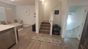 Een moderne keuken met een eethoek, houten vloeren en een trap die naar een ander niveau leidt.