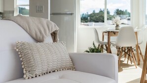 Una sala de estar moderna con un sofá, una manta decorativa y un cojín texturizado.