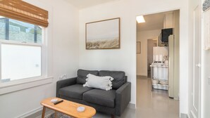 Una sala de estar moderna con un sofá gris, una pequeña mesa de madera y un cuadro en la pared.