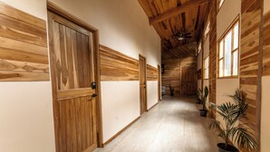 A hallway with wooden paneling, doors, and potted plants.