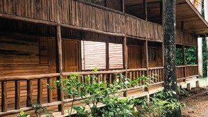 A wooden cabin with a balcony, surrounded by greenery.