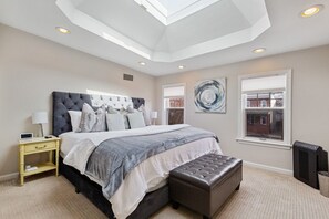 Une chambre à coucher avec un grand lit, un banc, une table de chevet et un radiateur.