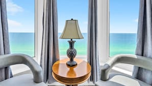 Ein Zimmer mit Blick auf das Meer, ein Tisch mit einer Lampe und zwei Stühle.