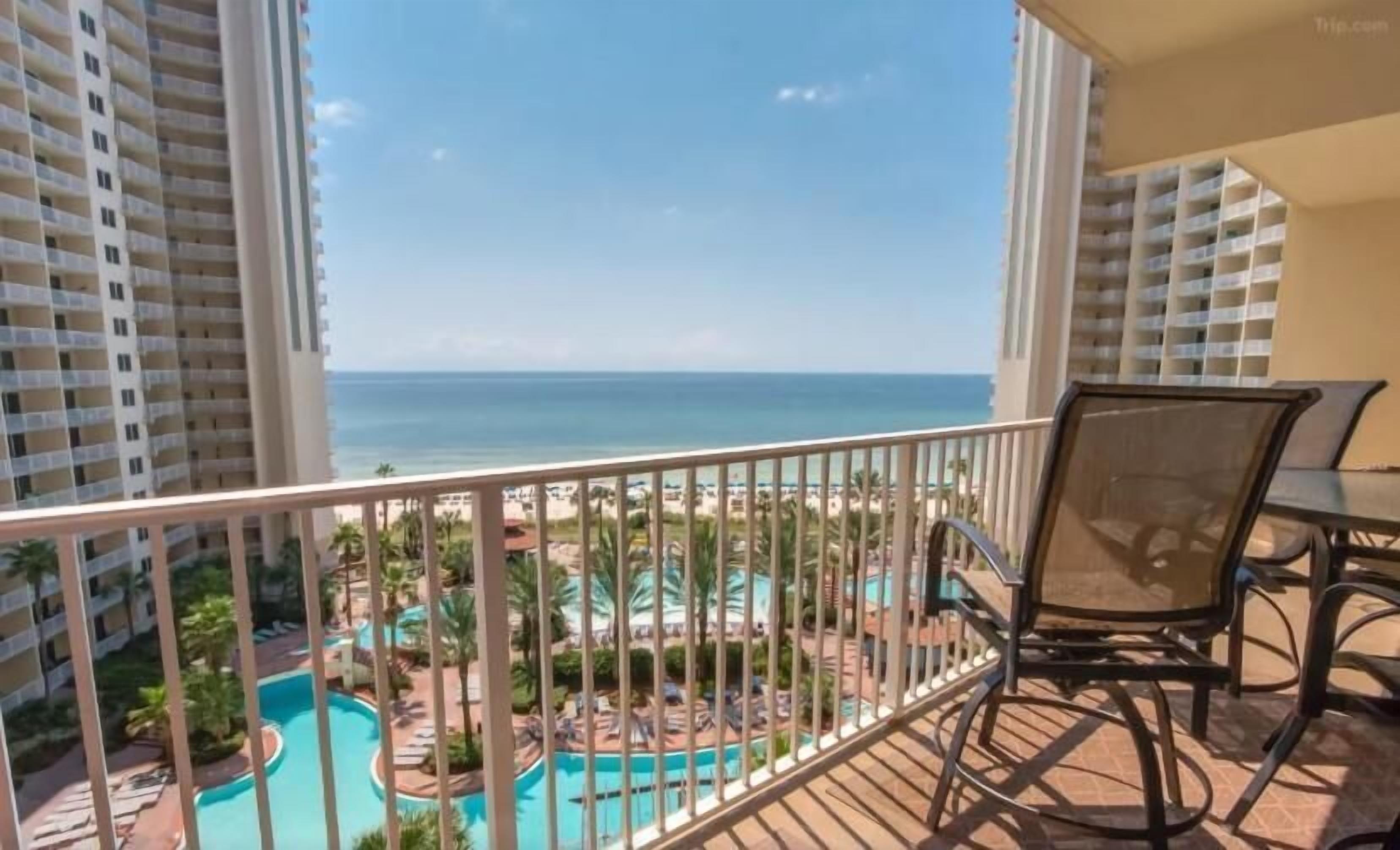 A balcony with a view of a pool and beach.
